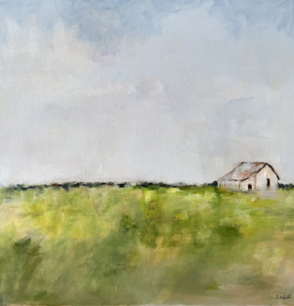 A white barn with a rusty roof in a green field